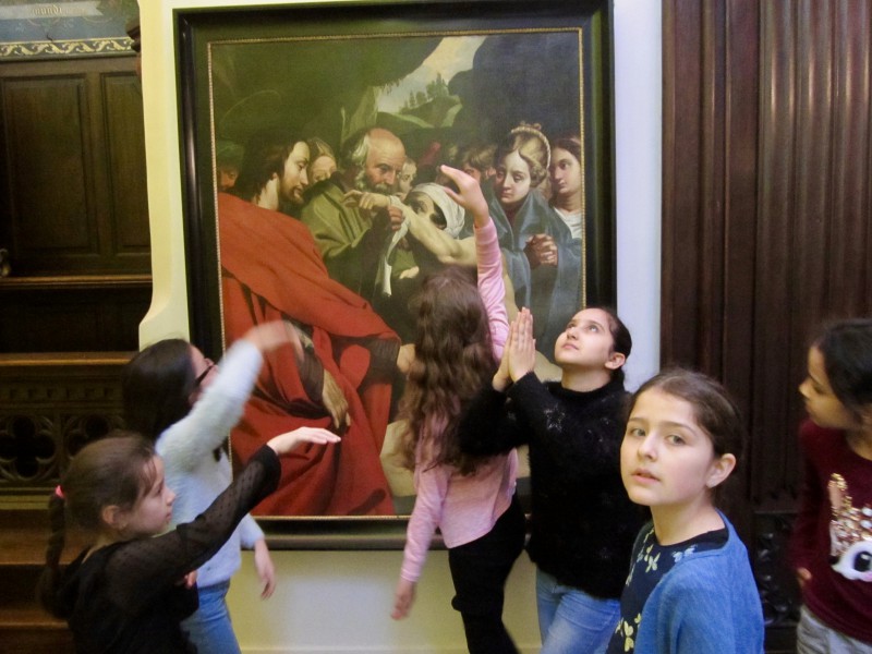 Kinderen springen rond barok schilderij in museumruimte