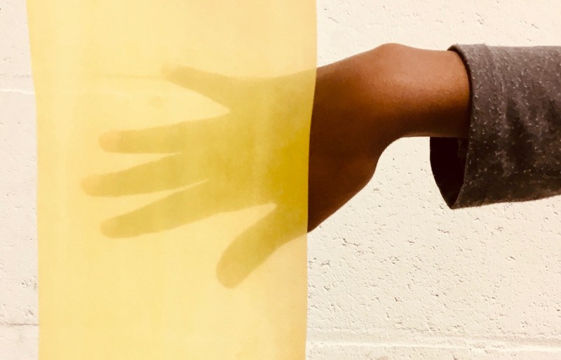 Kind houdt zijn hand voor felgeleurde cellofaan