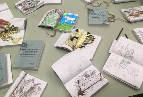 verschillende tekenschriften liggen opengeslagen op een tafel